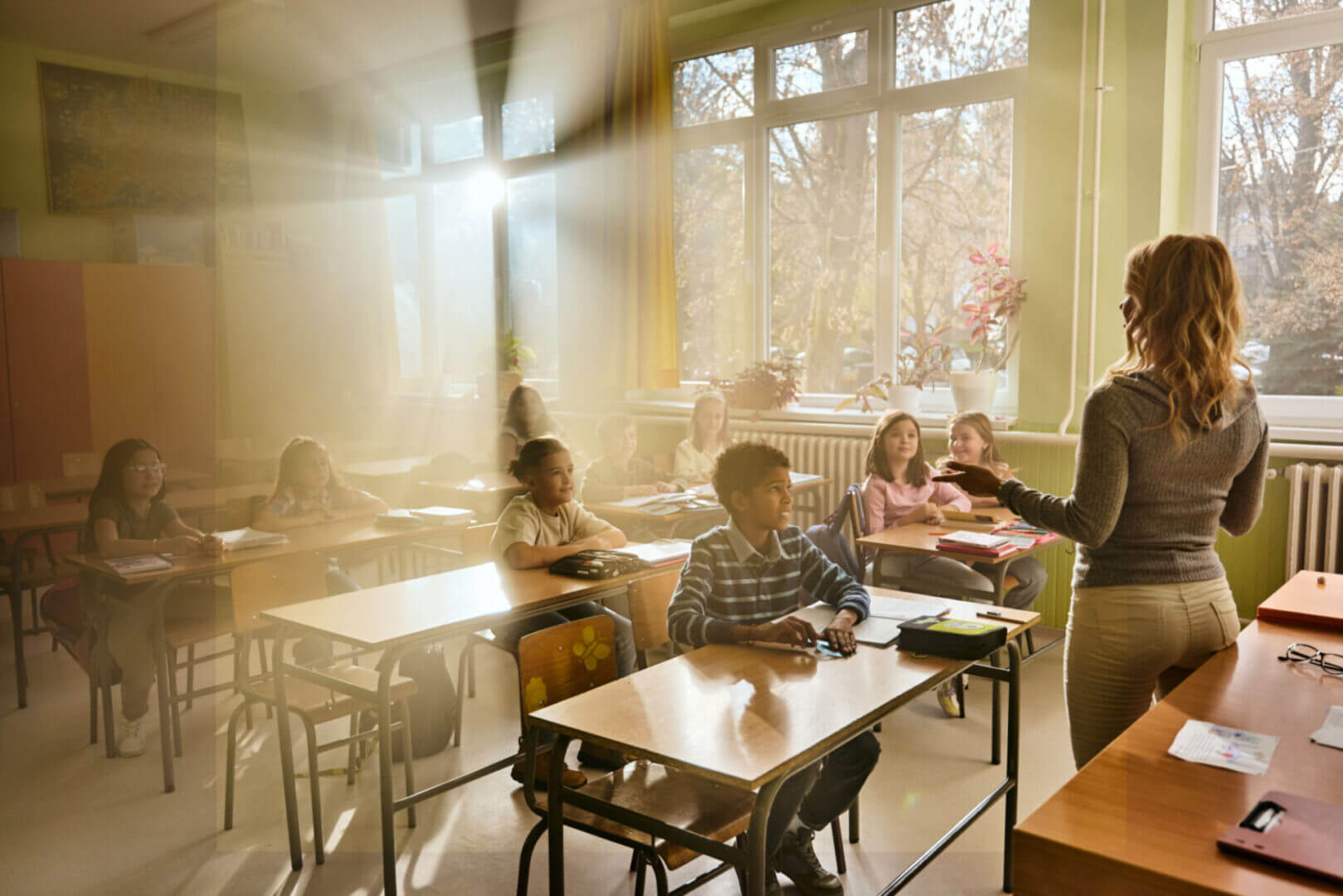 Sunlight streams into a classroom filled with students at their desks.