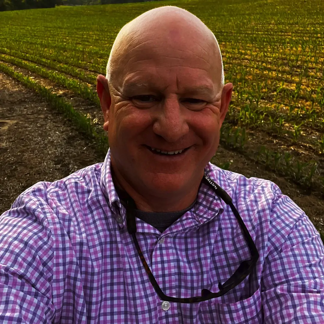 Smiling man outdoors in a field during daytime.